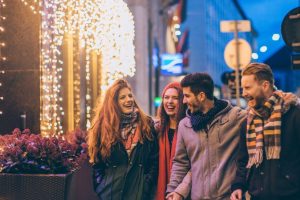 group of people laughing and walking in a christmas lit space